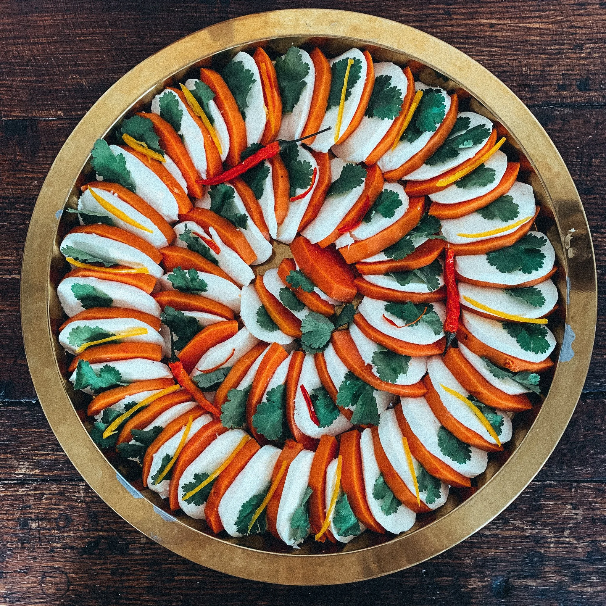Rundes Tablett mit Fingerfood, Orangenscheiben und Koriander